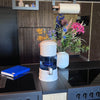 Aqualine waterfilter op kookfornuis met gekleurd bloemstuk en blauw schrift